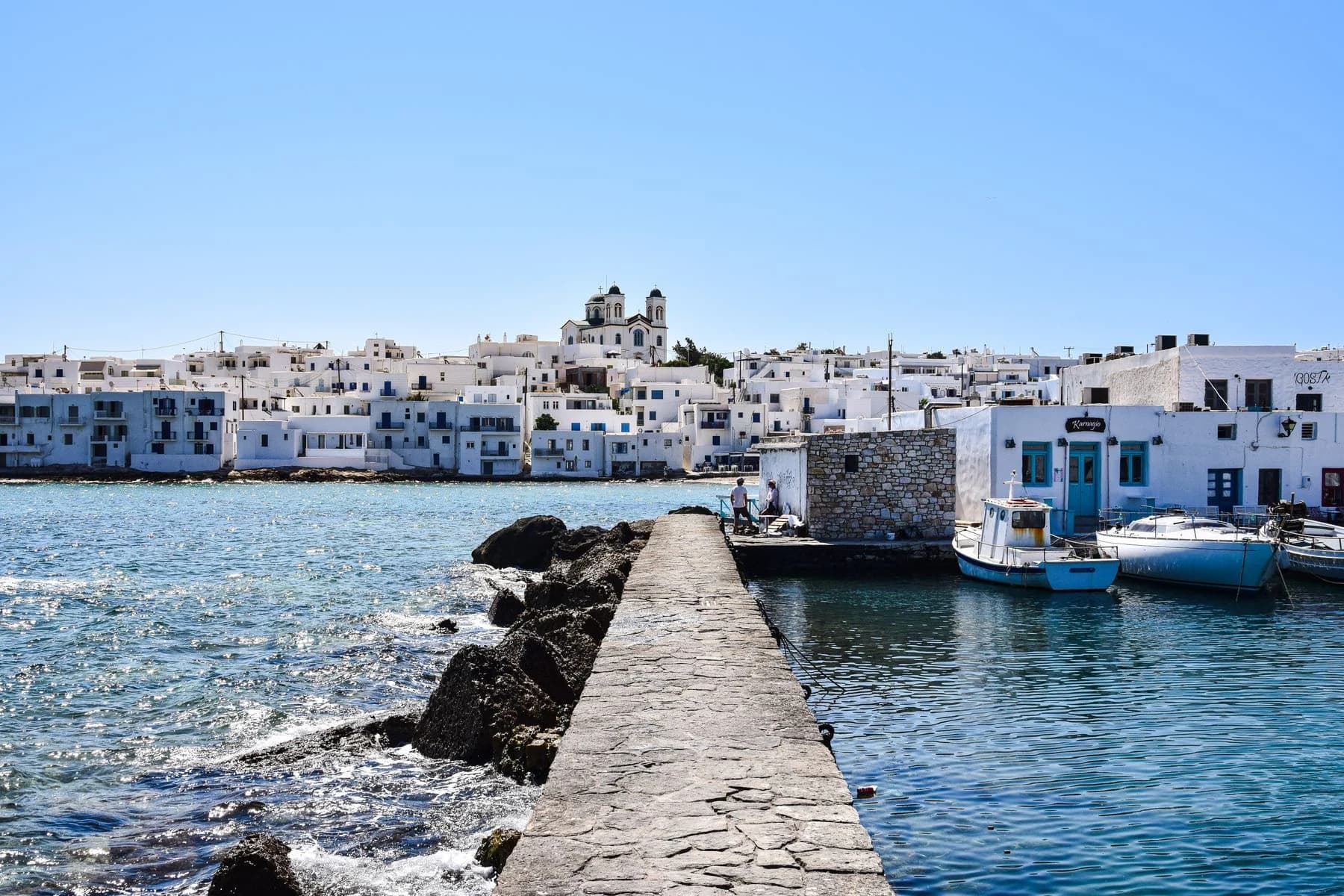 White waterfront houses, a stone pier and fishing boats in Naoussa, Paros